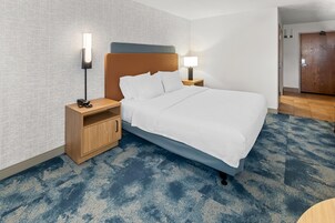Una habitación de hotel con cama, dos mesitas de noche, un armario de madera y una puerta.