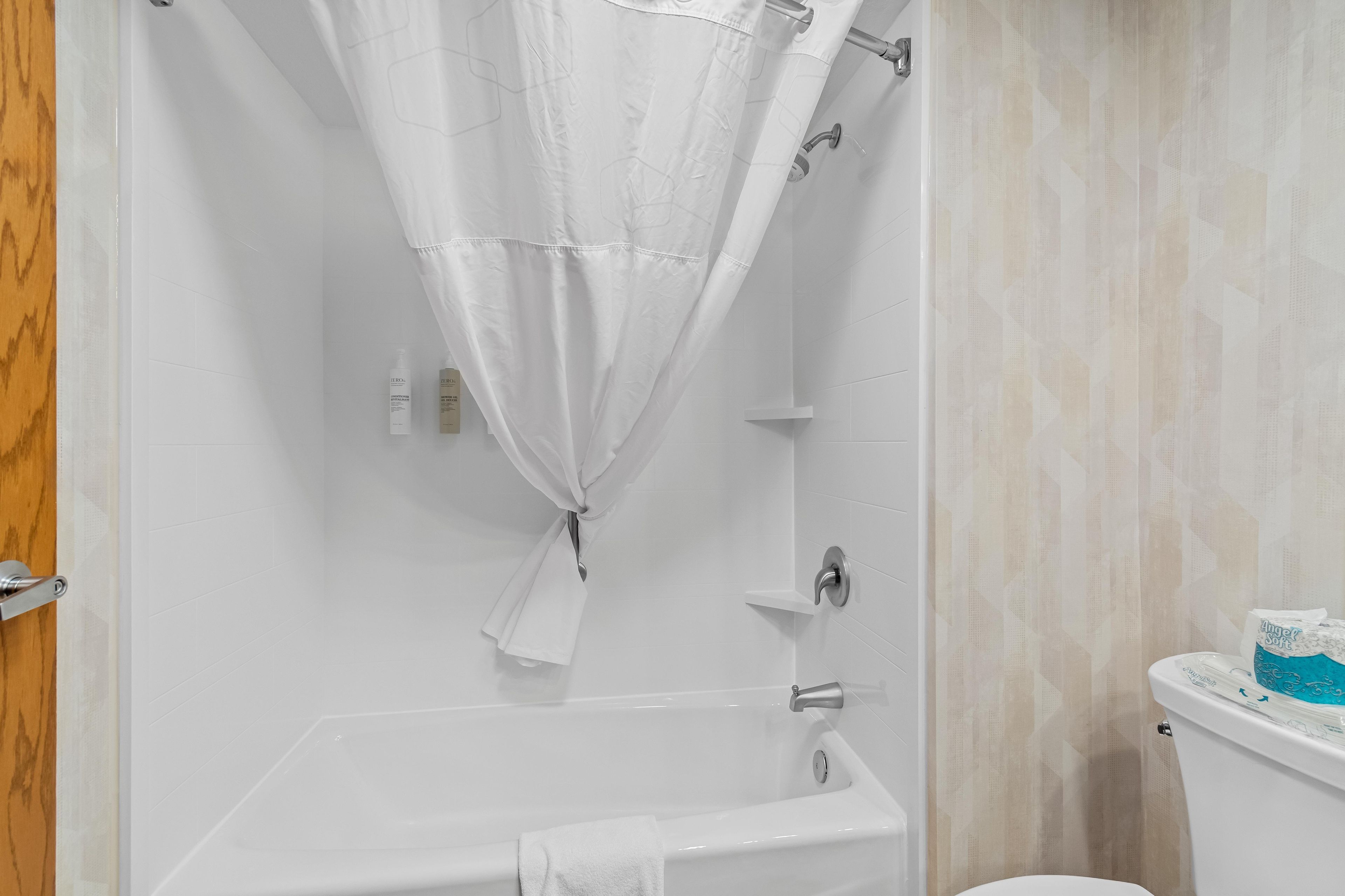 Un baño con bañera, inodoro y cortina de ducha.