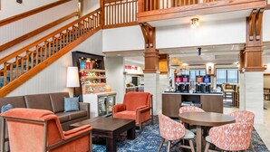 Een hotellobby met een trap, zithoek, koffiebar en uitzicht op zee.