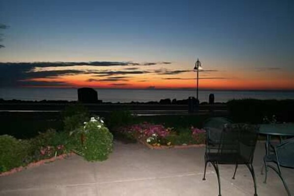 A patio with a view of the sunset over the ocean, a metal chair, and a table. - Hampton Inn Duluth Canal Park (Duluth)