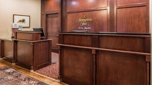 A reception desk with a framed animal picture and a sign for Hampton Inn Col Alto. - Hampton Inn Lexington-Historic District (Lexington)
