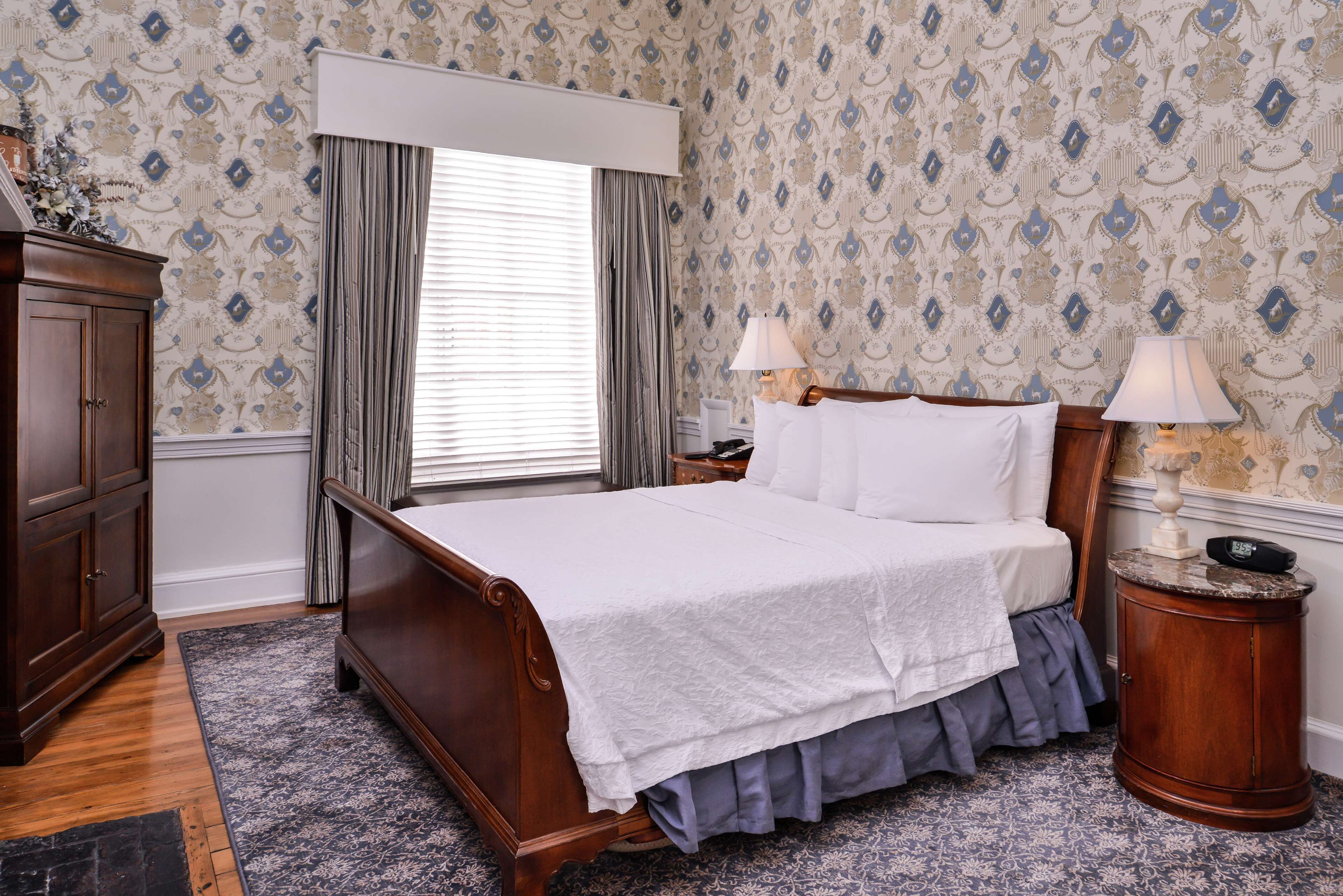Une chambre à coucher avec un lit en bois, deux lampes de chevet, une table de chevet et une commode.