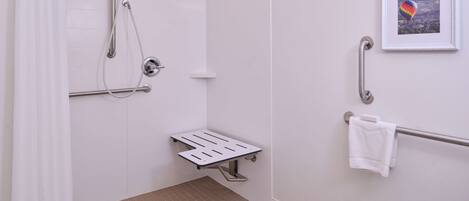 A bathroom with a shower, grab bar, and a towel rack.