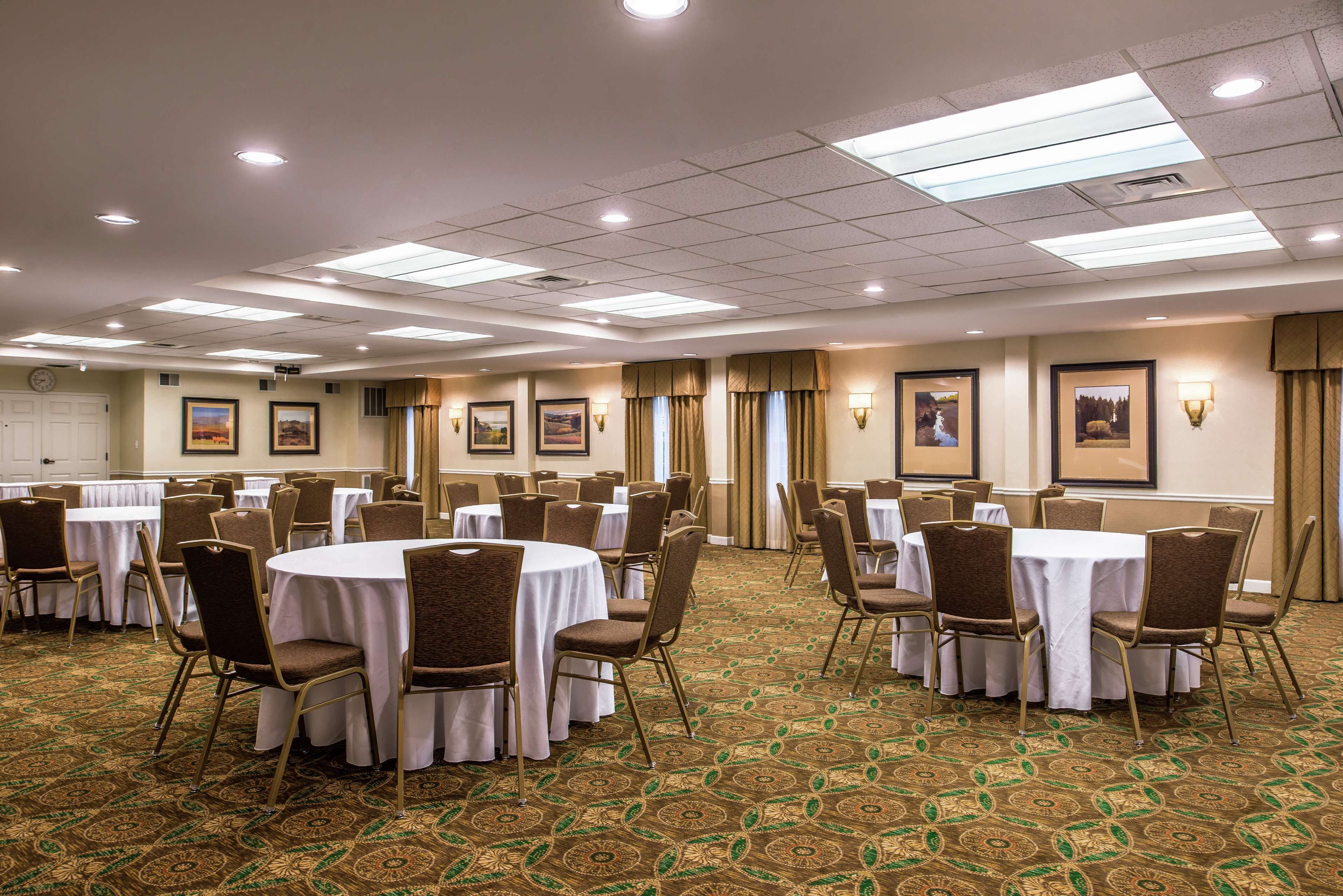 A conference room with round tables, chairs, and framed pictures on the walls.