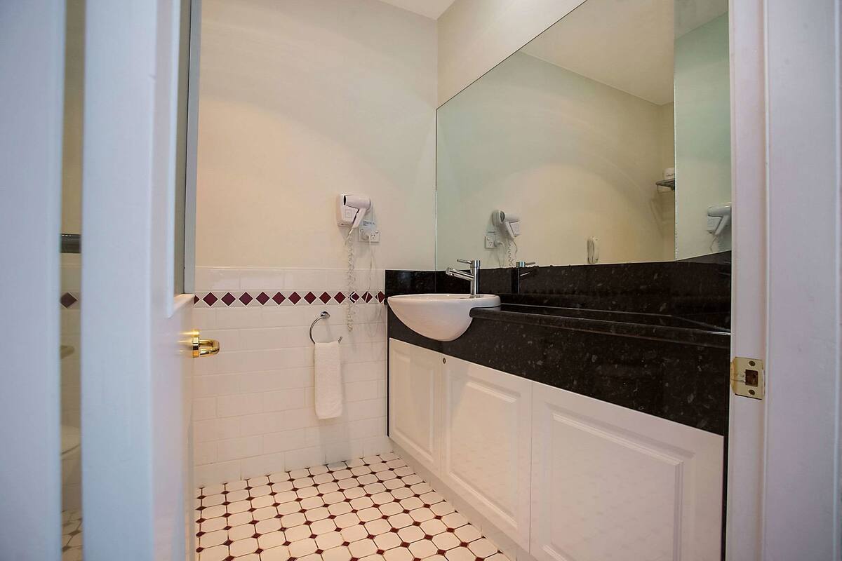 A bathroom with a white sink, black countertop, and a mirror above it.