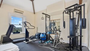Un gimnasio en casa con equipo de ejercicio, una ventana y un espejo.