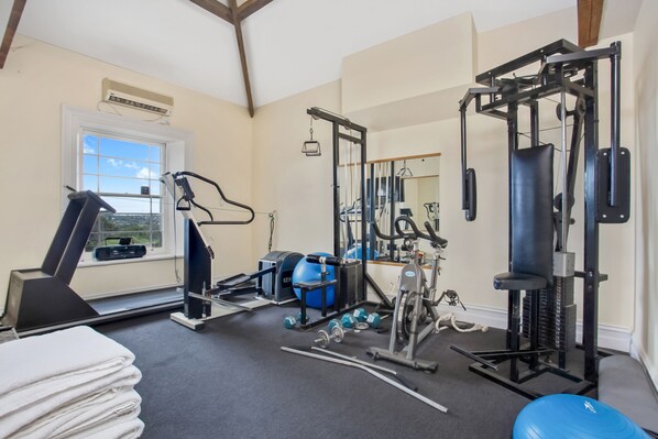 A home gym with exercise equipment, a window, and a mirror.