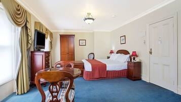 A hotel room with a bed, a desk, a chair, a television, and a wardrobe.