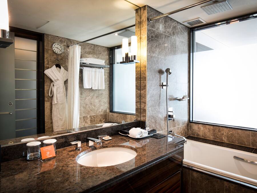 A modern bathroom with a large mirror, a sink, a bathtub, and a shower area.