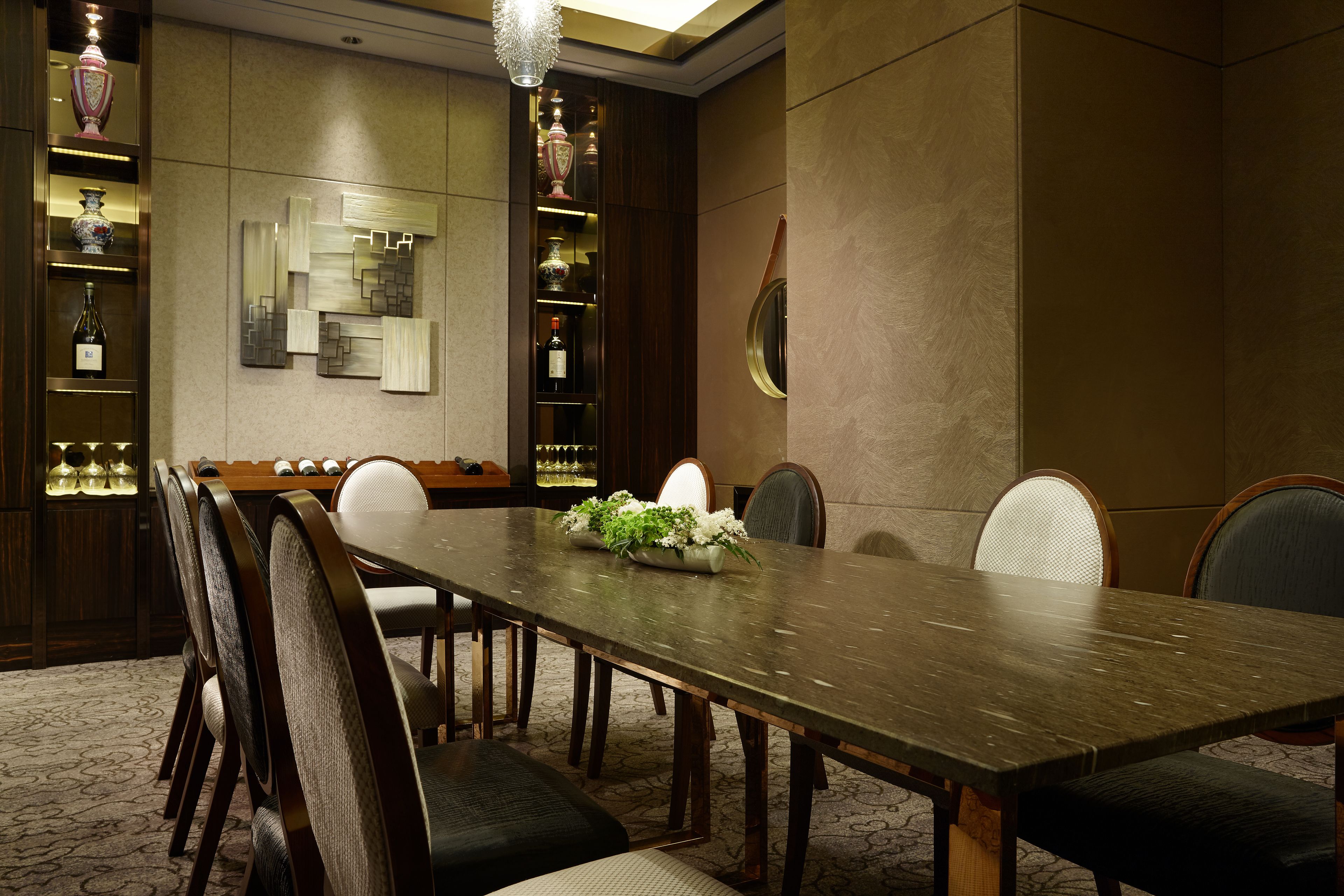 A conference room with a long table, chairs, and a decorative wall with shelves.