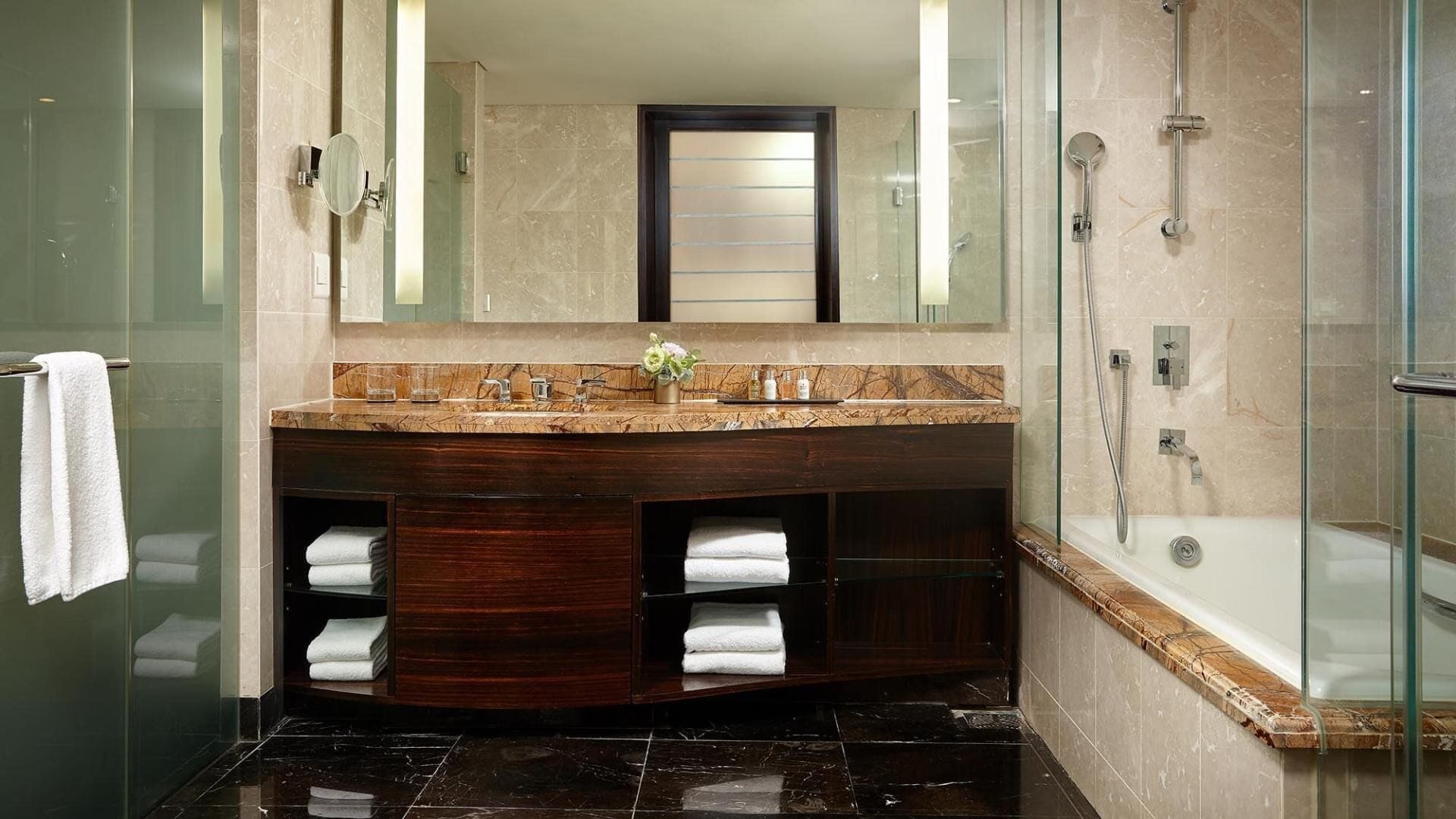 A modern bathroom with a glass-enclosed shower, a vanity with a marble countertop, and a large mirror above the sink.