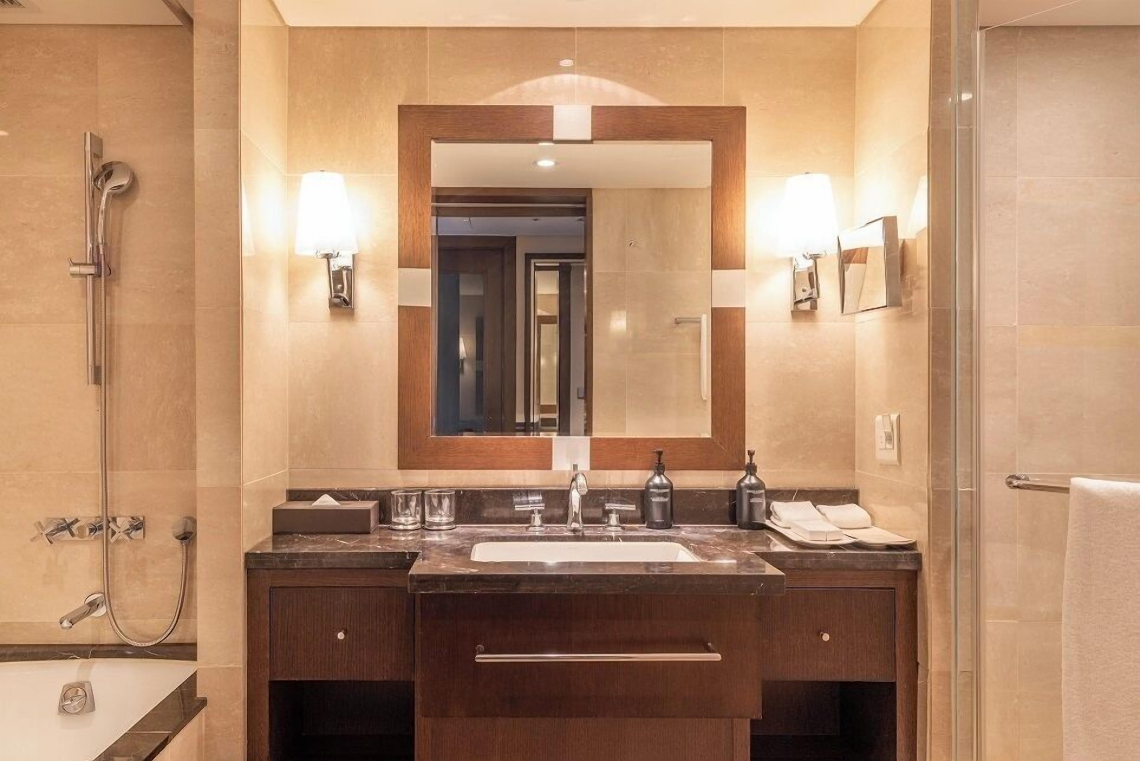 Une salle de bain moderne avec un grand miroir, deux vasques et une douche.