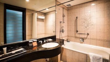 A modern bathroom with a curved black sink, a white bathtub, and a glass-enclosed shower area.