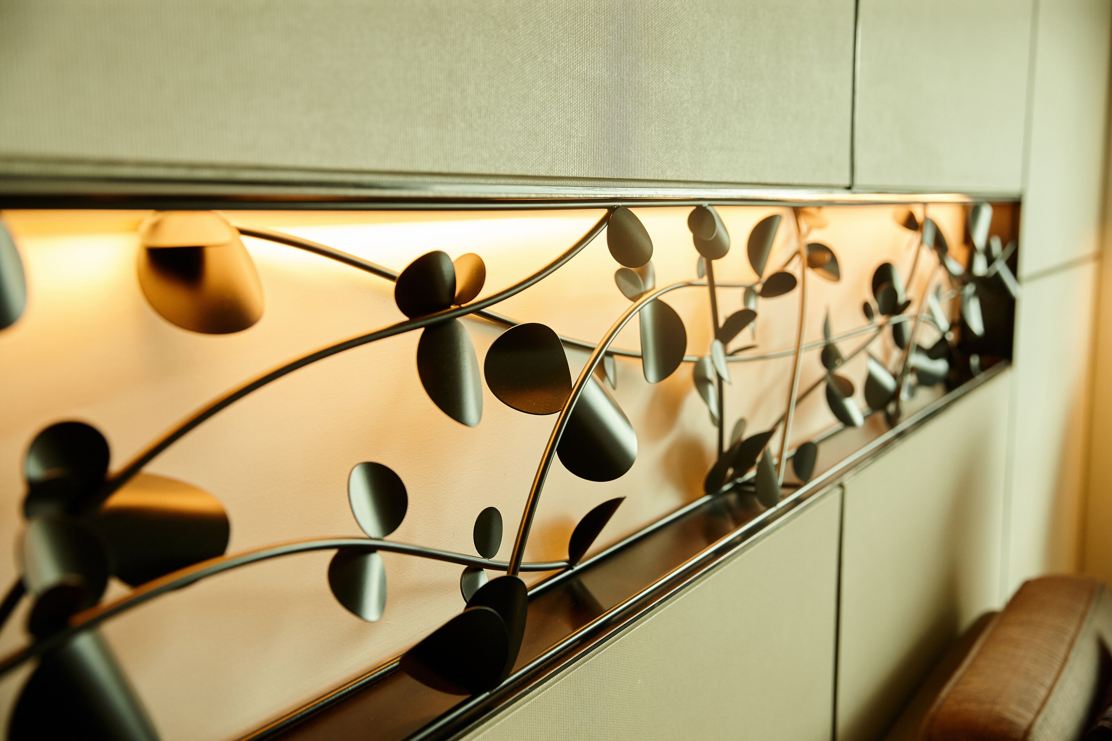 A modern interior with a metallic wall art piece featuring abstract shapes and a reflective surface.