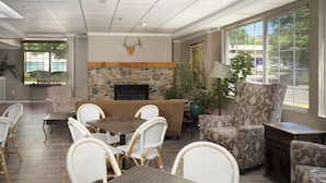 A spacious indoor area with a stone fireplace, wicker furniture, and large windows offering views of the outdoors.