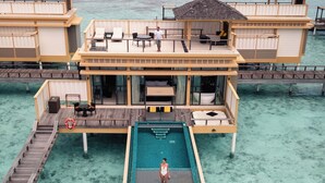 Bungalows über dem Wasser mit Pool, Holzterrasse und Meerblick.