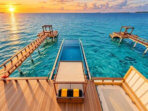 A wooden deck with a pool, lounge chairs, and a view of the ocean at sunset. - Angsana Velavaru - Free return Seaplane Transfers (Velavaru)