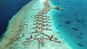 Overwater bungalows connect to a central pier, offering access to the turquoise waters.