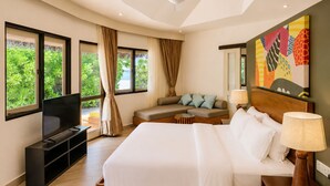 A hotel room with a bed, a sofa, a TV, and a painting on the wall. - Angsana Velavaru - Free return Seaplane Transfers (Velavaru)
