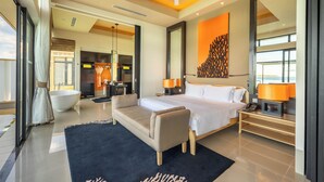 Ein modernes Hotelzimmer mit einem großen Bett, einer Sitzecke, einer Badewanne und Blick auf die Stadt.