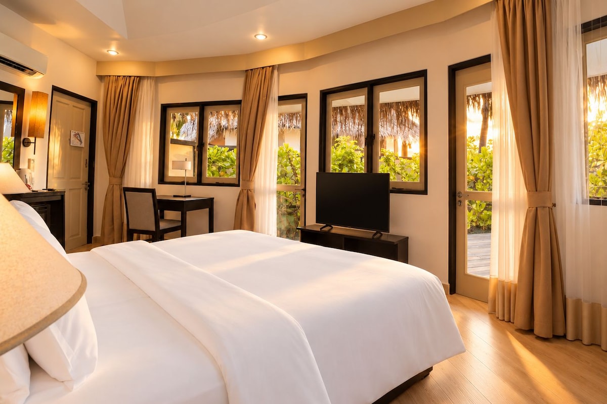 A hotel room with a large bed, a desk, a television, and windows with curtains.