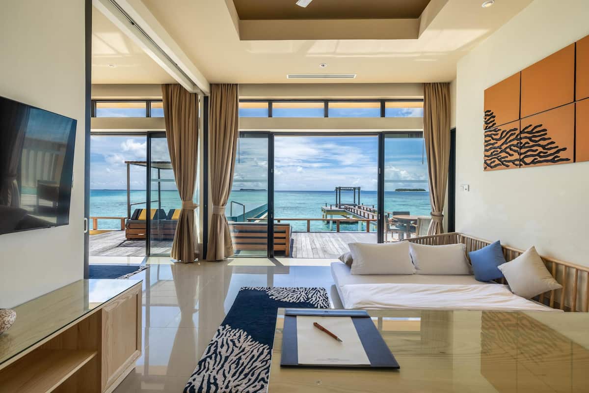 A modern hotel room with a large window offering a view of the ocean and a deck.