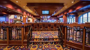 A hotel lobby with a central staircase, multiple seating areas, and large windows providing natural light.
