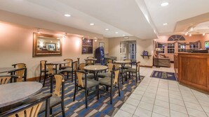 A hotel lobby with round tables and chairs, a reception desk, and a large mirror on the wall. - Baymont Inn & Suites by Wyndham Anchorage Airport (Anchorage)