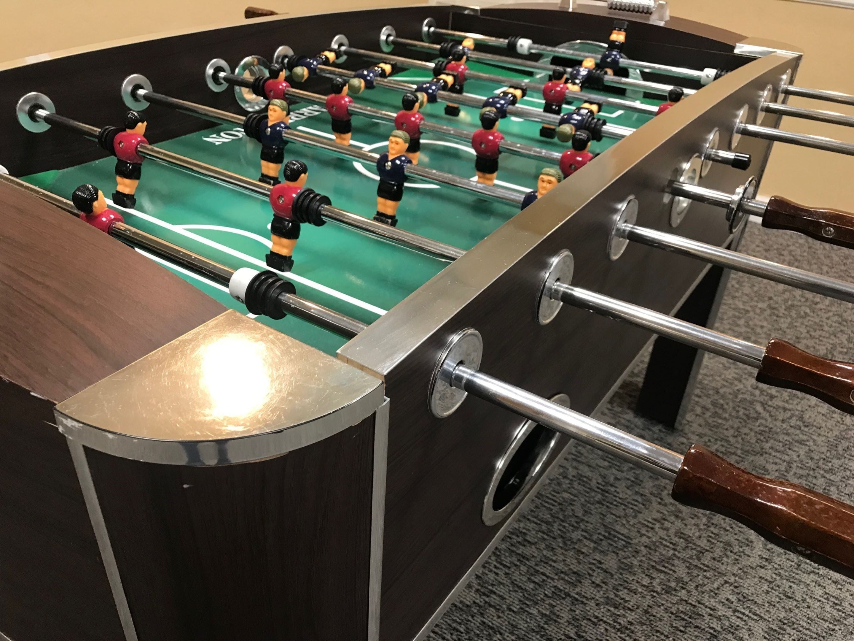 A foosball table with a metallic frame and wooden handles.