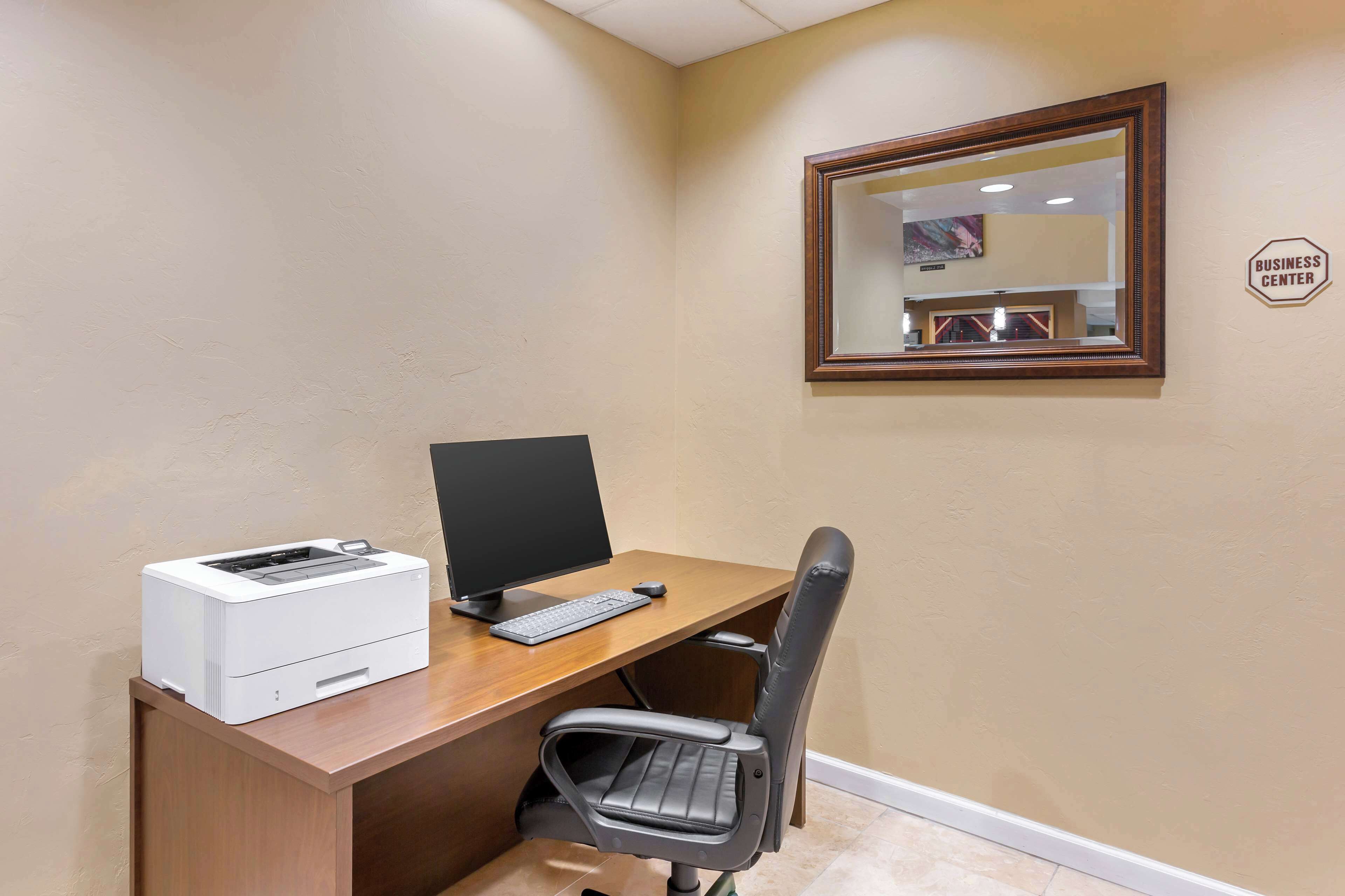 A small office space with a desk, computer, printer, and a chair.