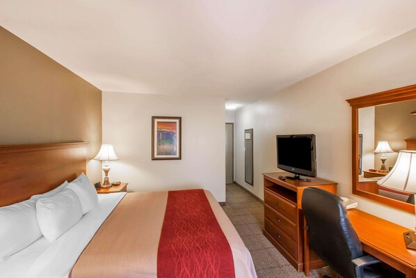 A hotel room with a bed, a desk, a television, a mirror, and a painting on the wall. - Quality Inn & Suites Germantown North (Germantown)