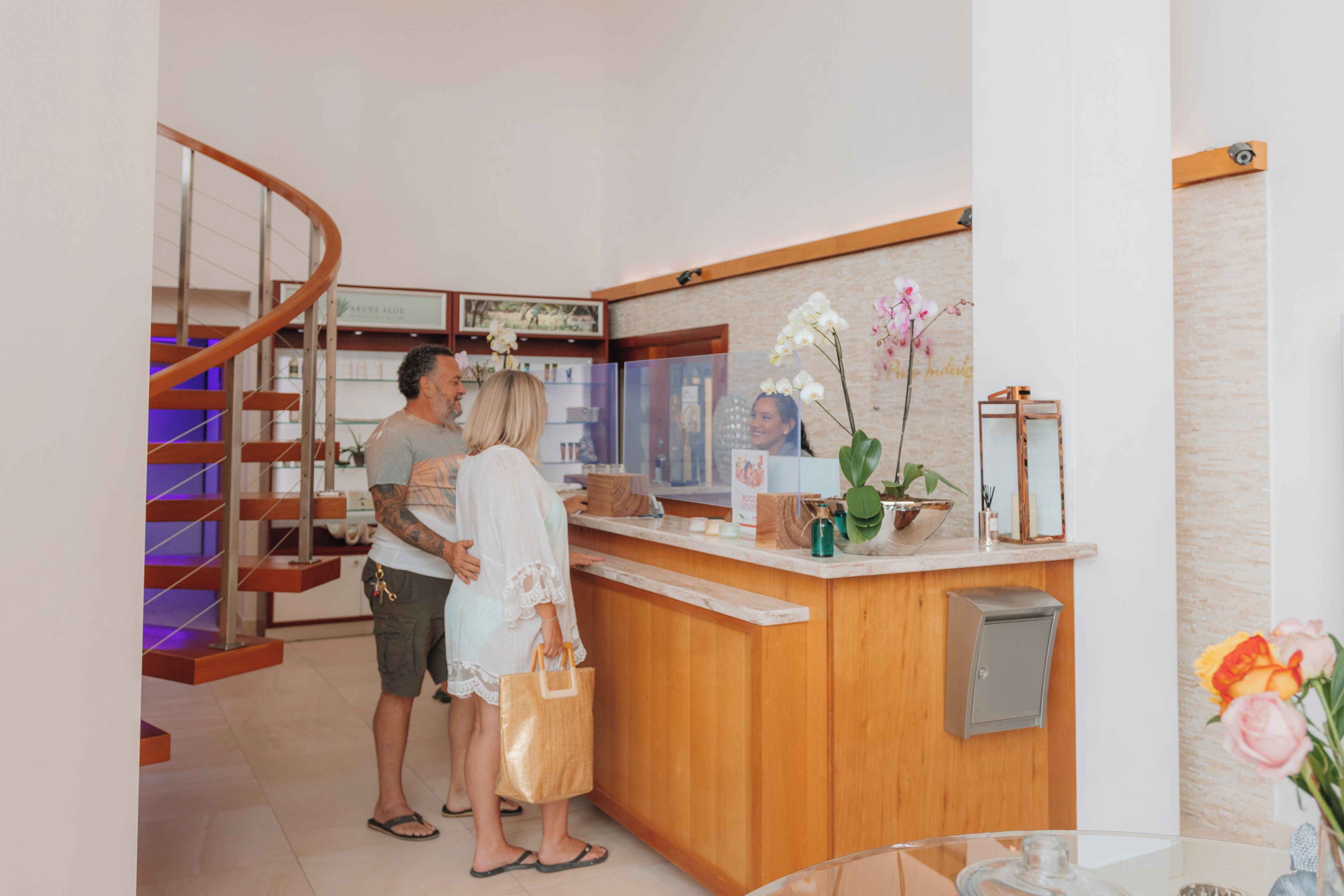 Un espace d’accueil comprenant un comptoir en bois, une vitrine et un escalier avec des rampes en bois.