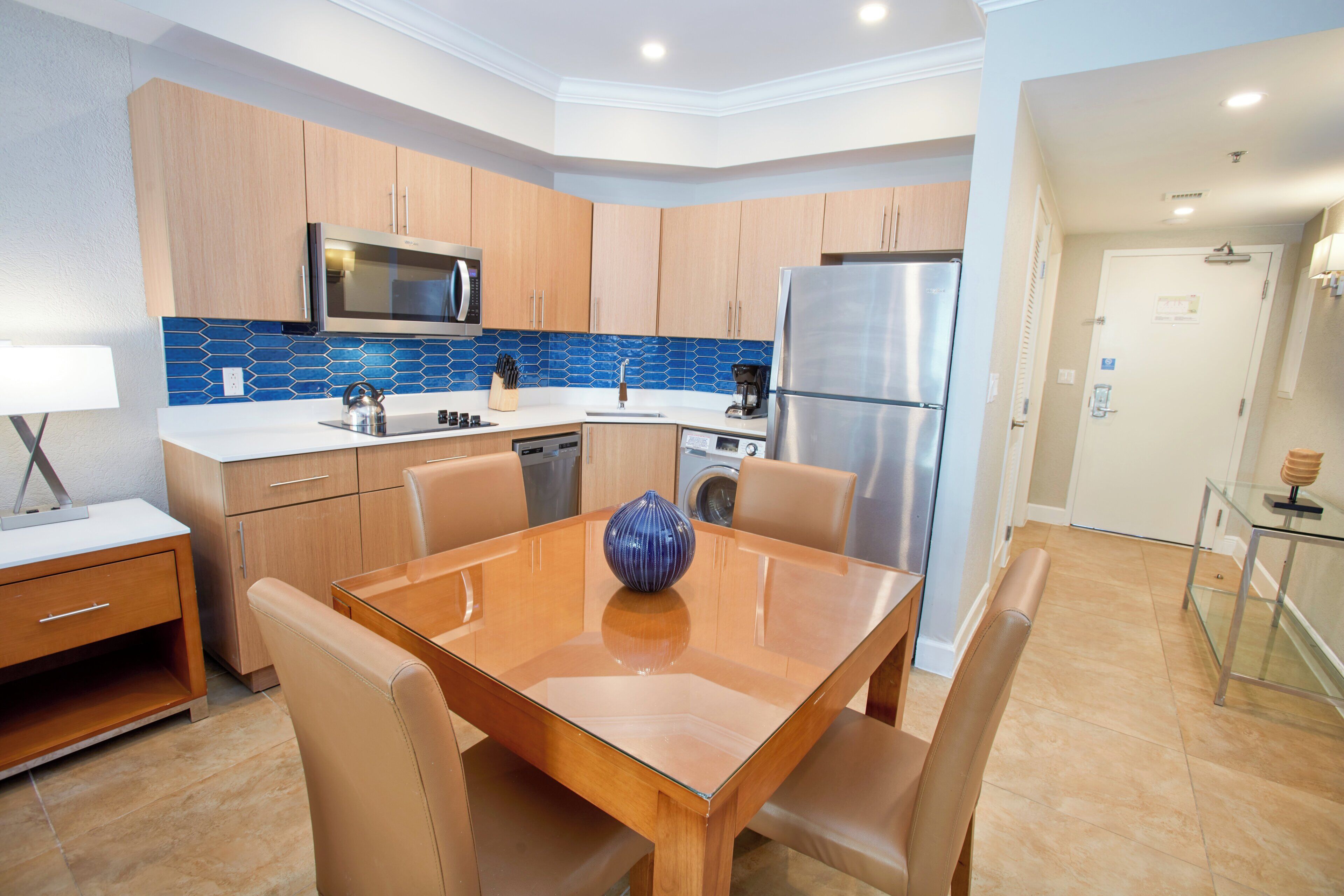Una cocina moderna con armarios de madera, electrodomésticos de acero inoxidable y una mesa de comedor de vidrio.