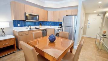 Una cocina moderna con armarios de madera, electrodomésticos de acero inoxidable y una mesa de comedor de vidrio.