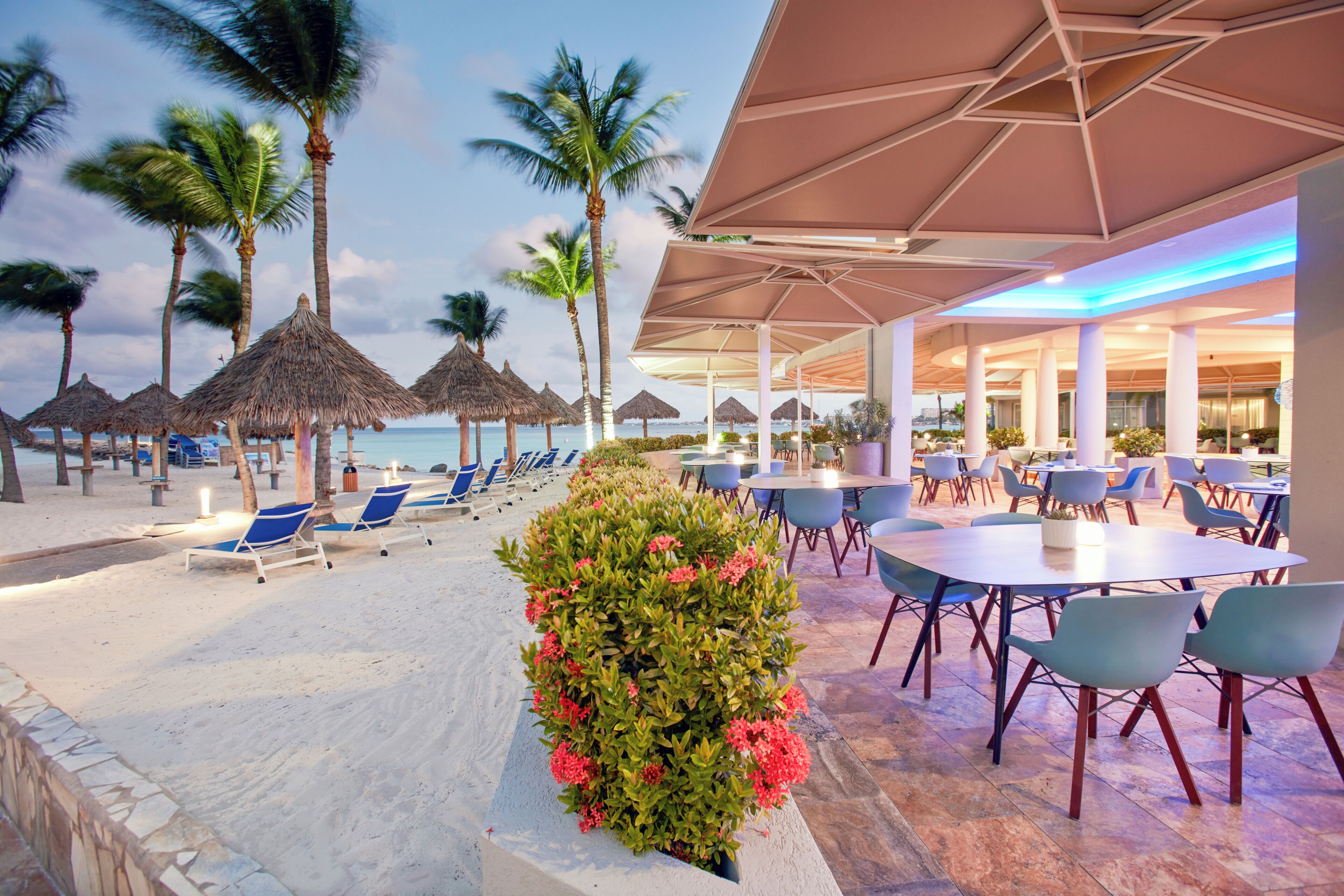 Ein Restaurant direkt am Strand mit Terrassenplätzen, Palmen und Meerblick.