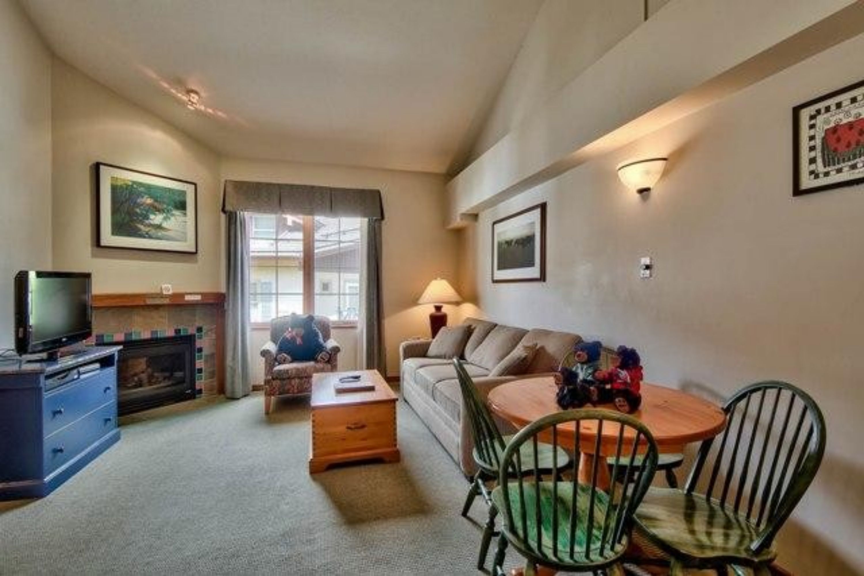 Un salon confortable avec une cheminée, un téléviseur, un canapé, une table basse et un coin repas avec des chaises.