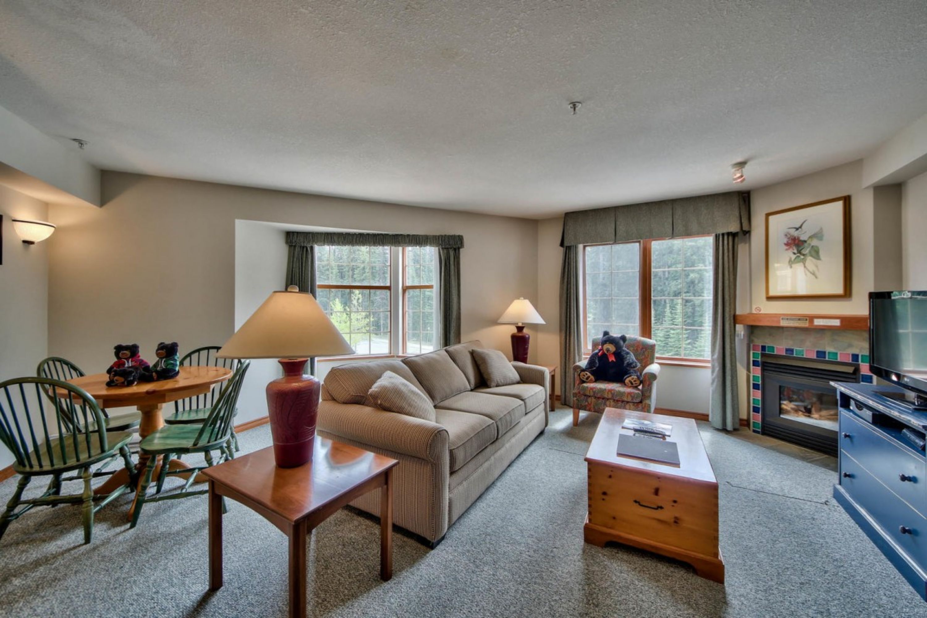 A cozy living room with a sofa, a coffee table, a fireplace, and a television.