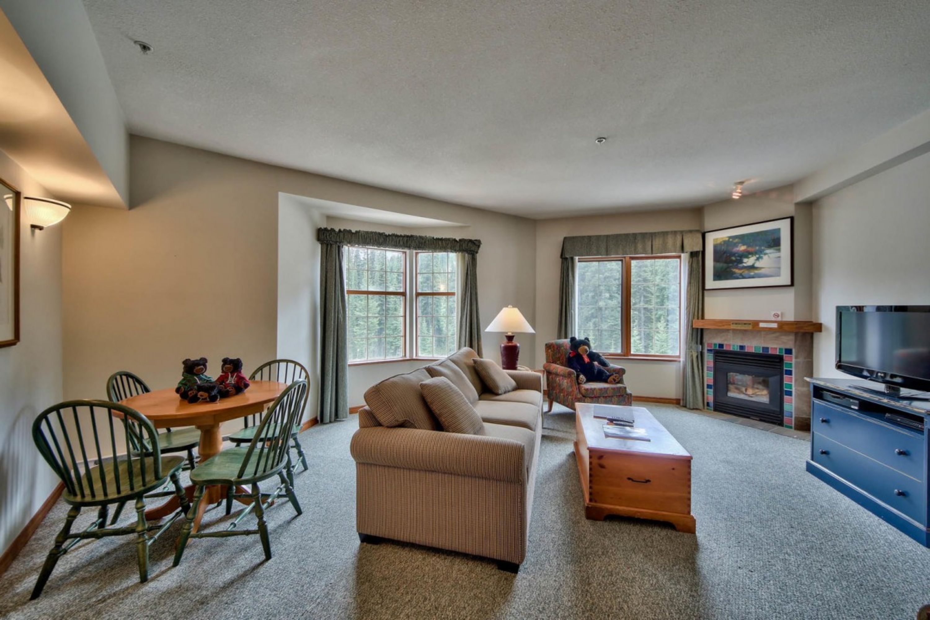 A cozy living room with a sofa, dining table, chairs, a TV, and a fireplace.