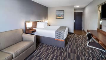 A hotel room with a bed, a sofa, a desk, and a TV.