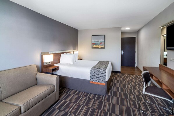 A hotel room with a bed, a sofa, a desk, and a TV. - Microtel Inn & Suites by Wyndham Pooler/Savannah (Pooler)