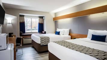 Une chambre d’hôtel avec deux lits, un bureau, une chaise, une télévision et une fenêtre avec des rideaux.
