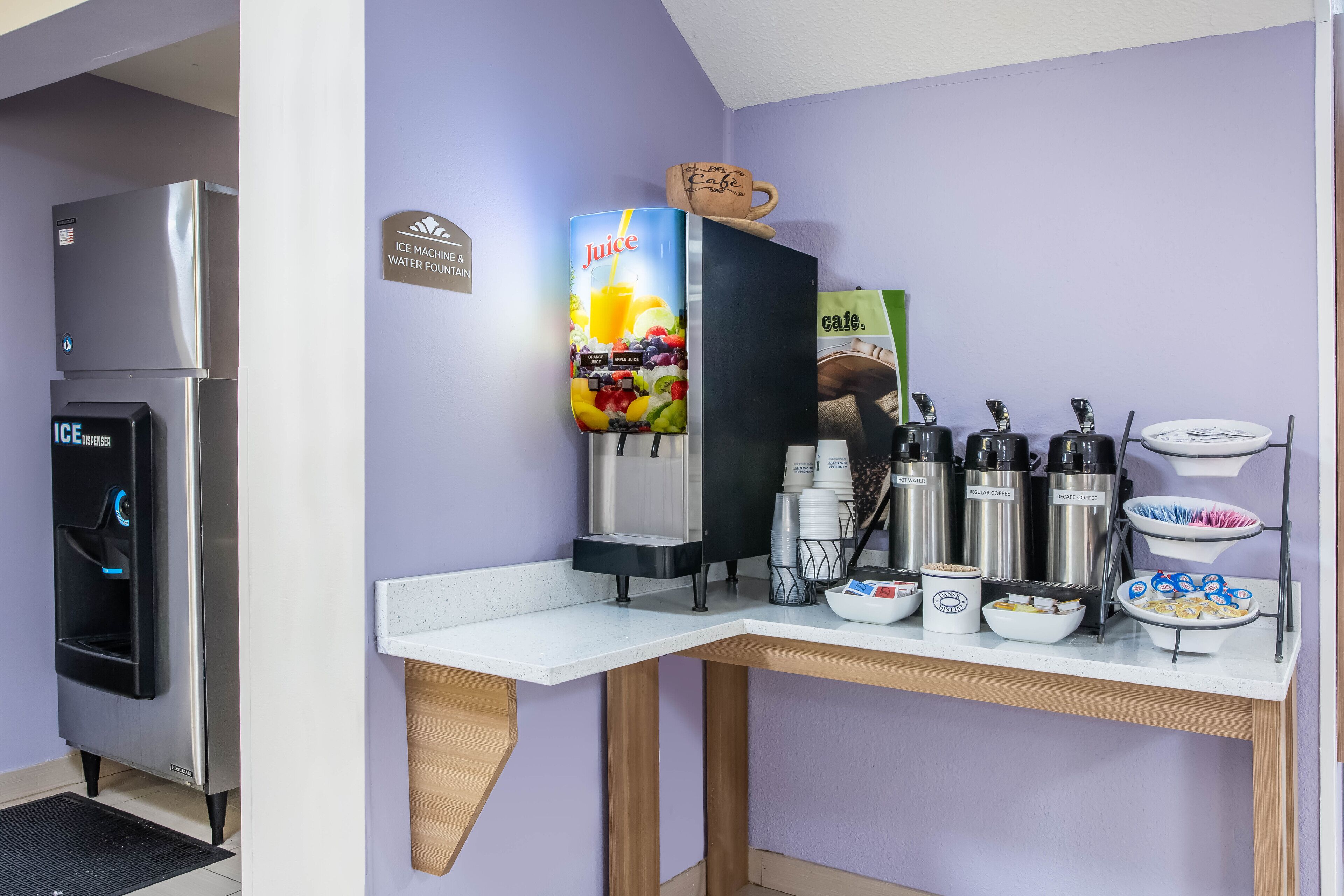 A kitchenette with a refrigerator, ice and water dispenser, juice dispenser, coffee makers, and a coffee station.