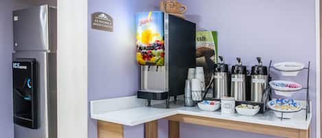 A kitchenette with a refrigerator, ice and water dispenser, juice dispenser, coffee makers, and a coffee station.