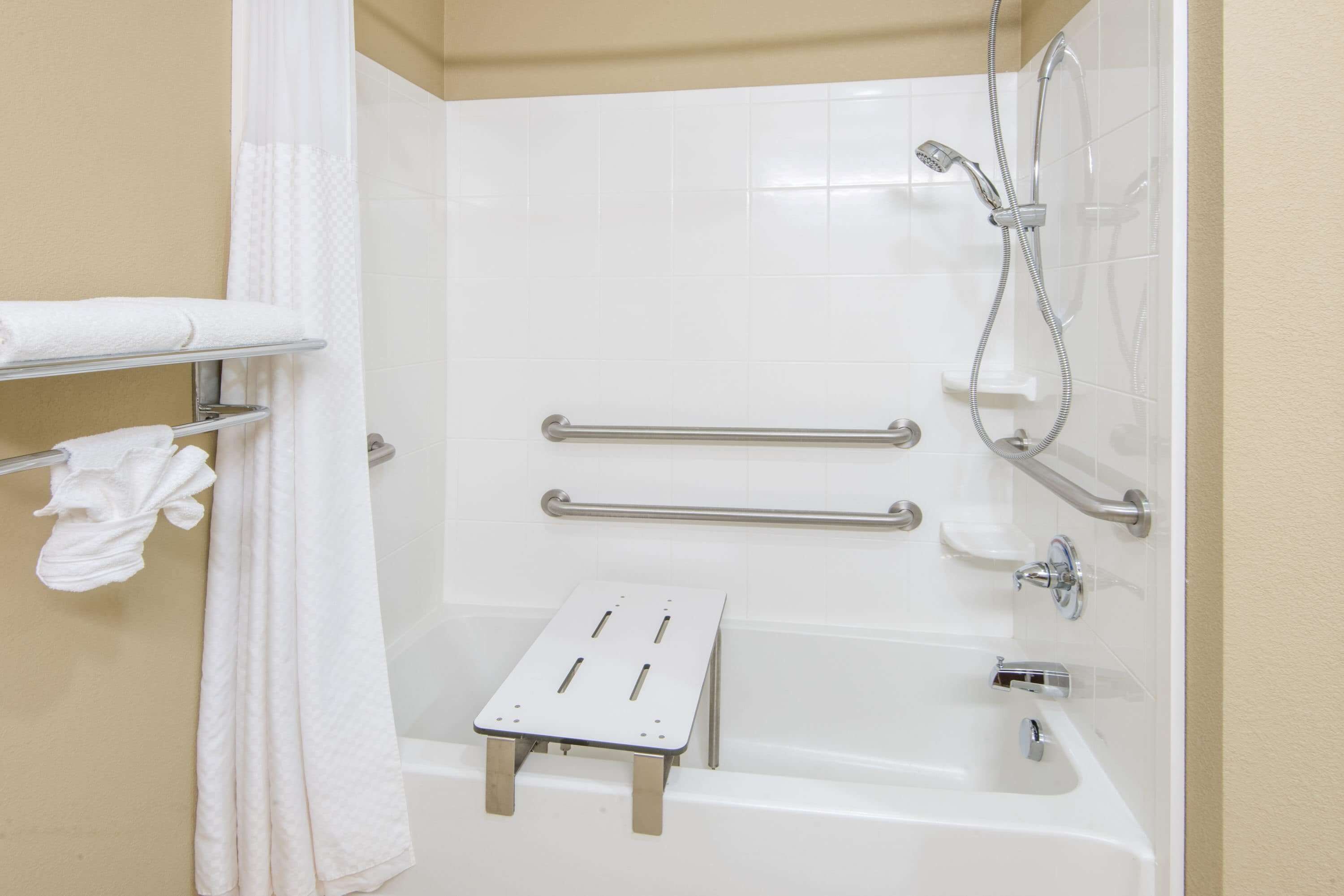 Un baño moderno con bañera, ducha y barras de apoyo.