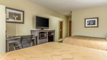 A hotel room with two beds, a desk with a television, a microwave, and a chair.