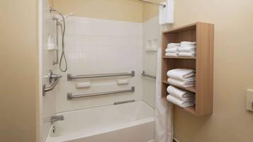Ein Badezimmer mit Badewanne, Dusche und einem Holzregal mit Handtüchern.