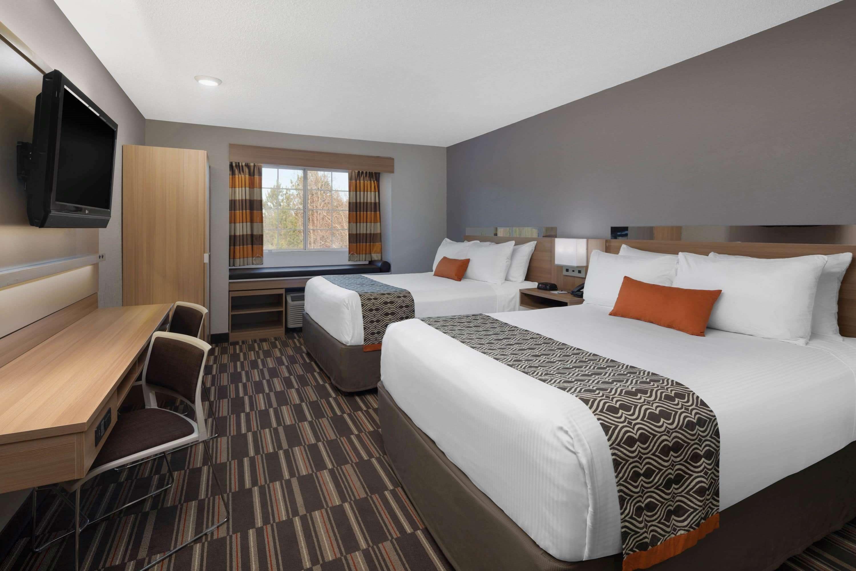 A hotel room with two beds, a desk, and a TV.