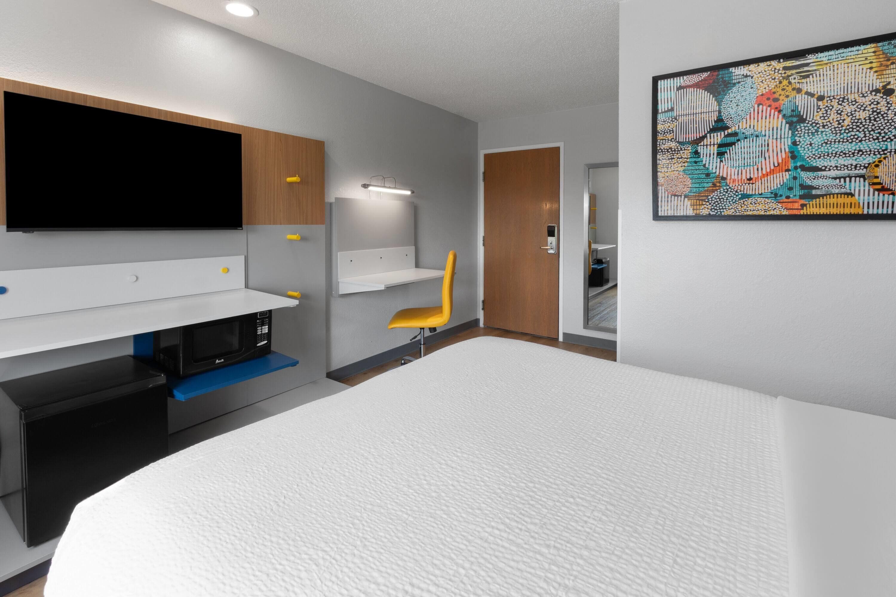 Een moderne hotelkamer met een groot bed, een flatscreen televisie, een magnetron en een klein bureau.