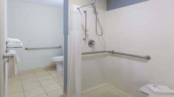 Une salle de bain équipée d’une douche, de toilettes et de barres d’appui.