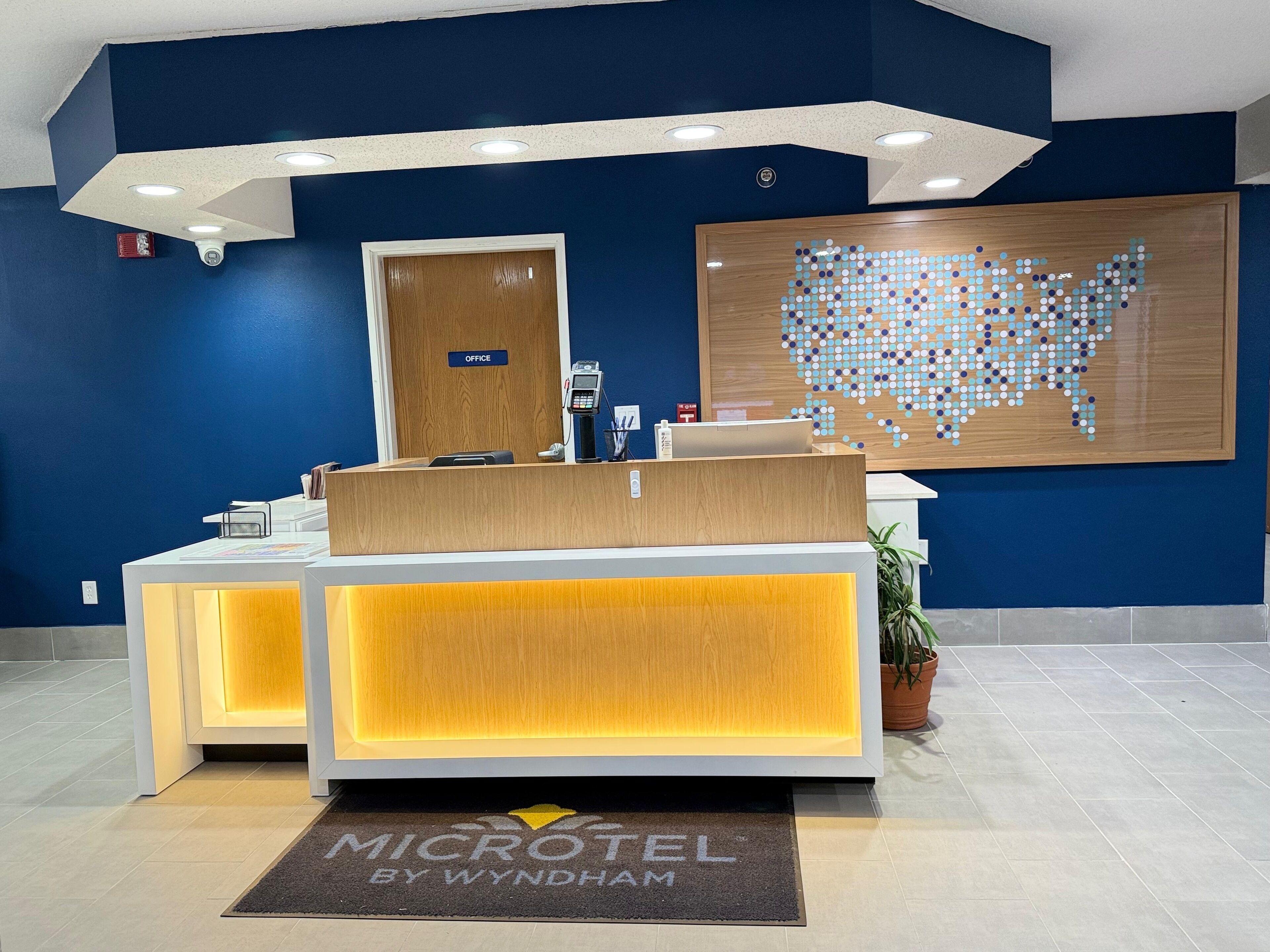 A reception desk with a wooden finish, a digital screen, and a sign indicating an office.